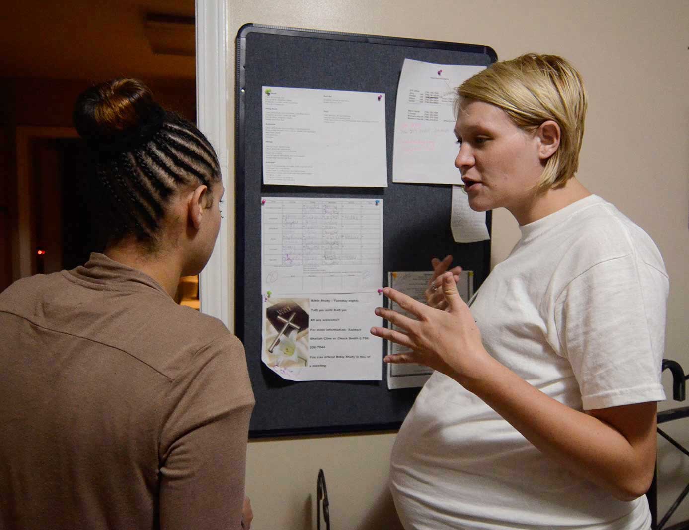 Stephanie, right, shows Dominique the chore list, just hours after Dominique's arrival at the Carter Hope Center.