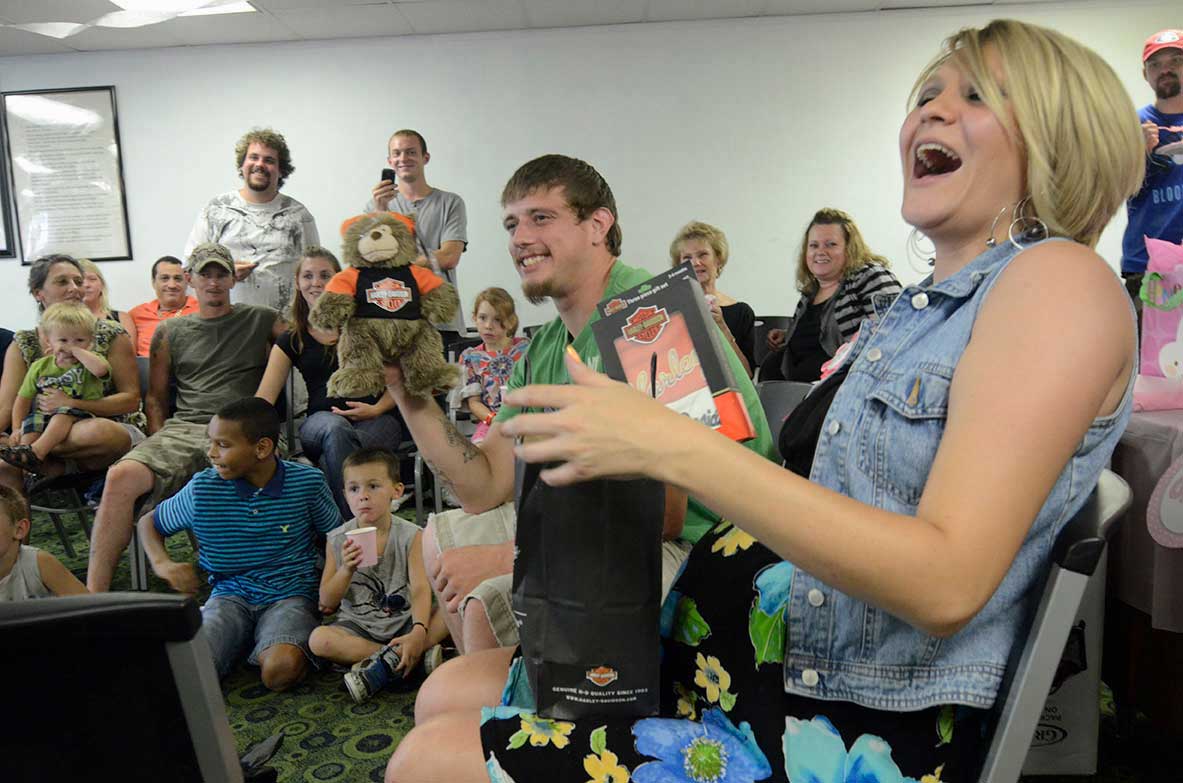 Stephanie, right, and Justin hold up a Harley Davidson gifts that Trevor Beebe gave them at their baby shower in Dalton, Ga.