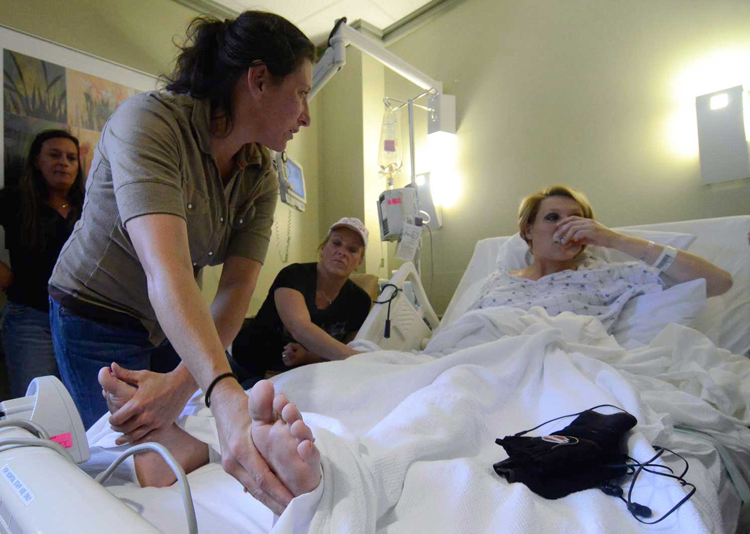 Stephanie's mother rubs her feet after her C-Section to deliver Journey. Terri, left, and Crystal look on.