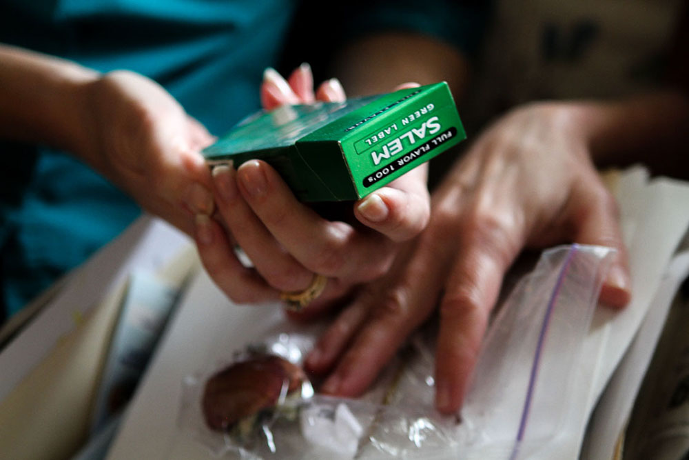 Gloria holds Bubba's last box of cigarettes, something she grabbed from his room in the basement after the suicide to feel a little closer to him.