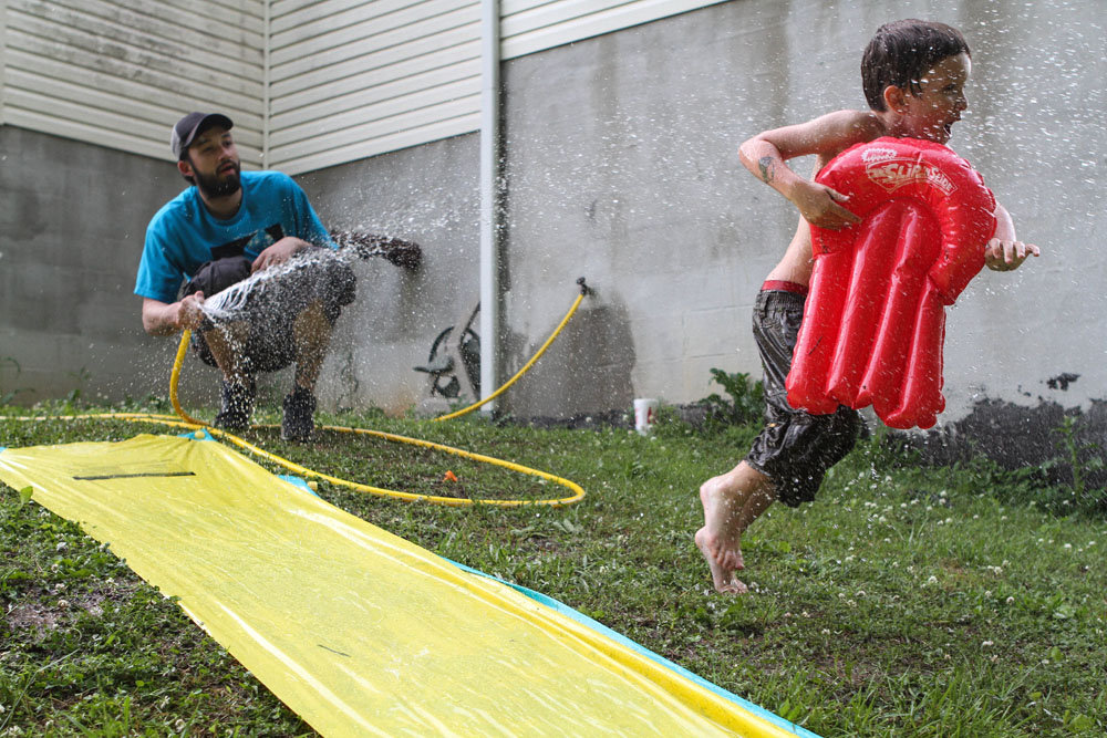 Ryan diverts the hose from the slip-and-slide to splash his son Malachi, in the backyard of his mother's house. She has custody of the boy, although Ryan visits often.